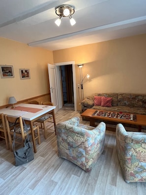 Un salon comprenant une table à manger, des chaises, un canapé et un lampadaire.
