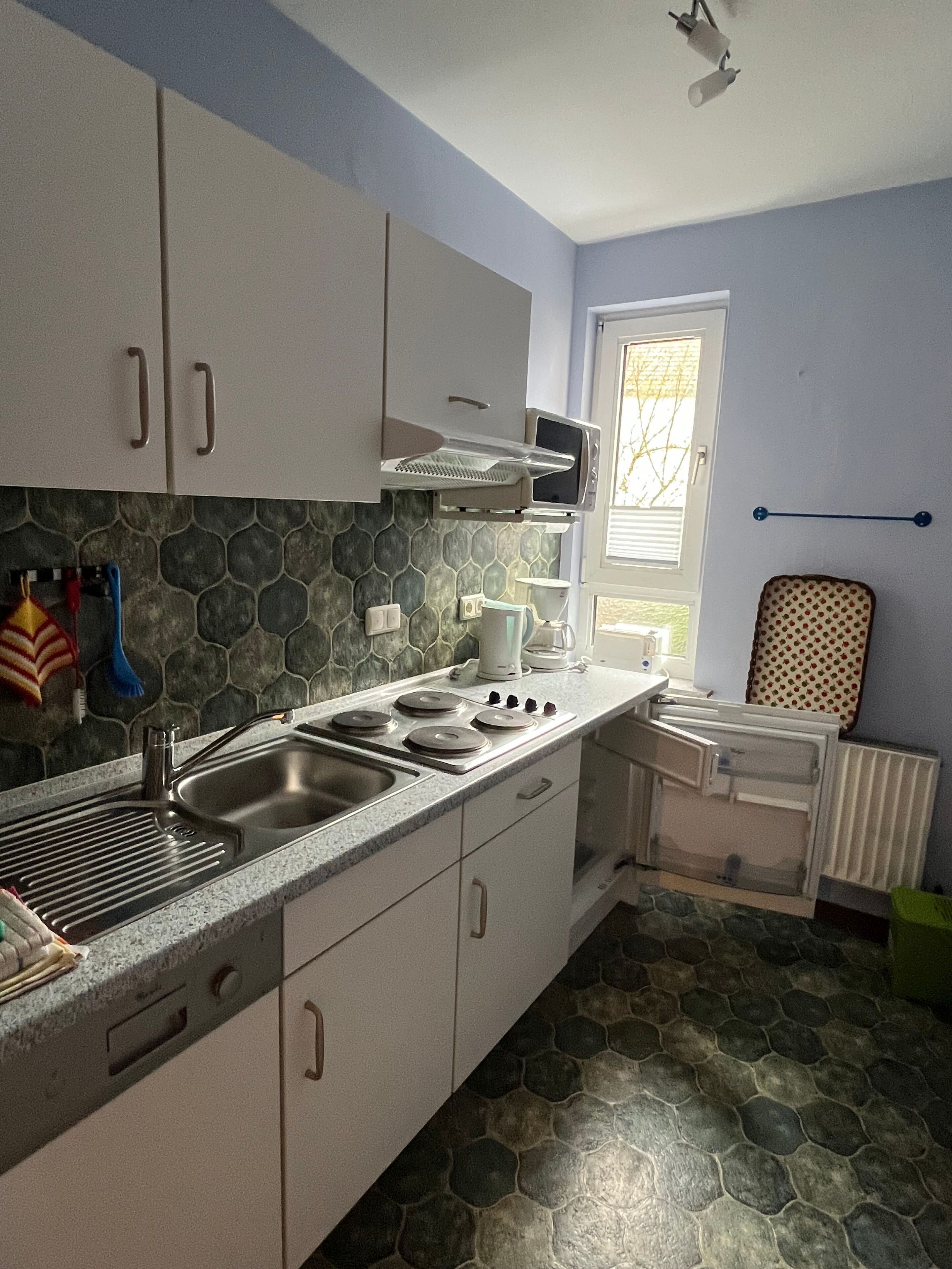 Cocina con armarios blancos, encimera de granito, estufa y microondas.