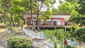 A two-story building with a balcony, surrounded by trees and vegetation. - 4 bedroom beautiful home in Brela (Brela)