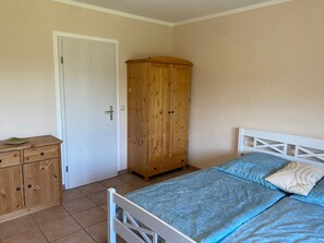 A bedroom with a bed, a wooden wardrobe, and a door. - Double room (apartment 3) - log cabin (Sangerhausen)
