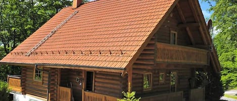 A log cabin with a sloped roof, a porch, and a chimney.
