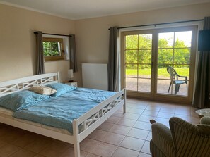 A bedroom with a bed, a nightstand, a window, and a view of greenery outside. - Double room (apartment 3) - log cabin (Sangerhausen)