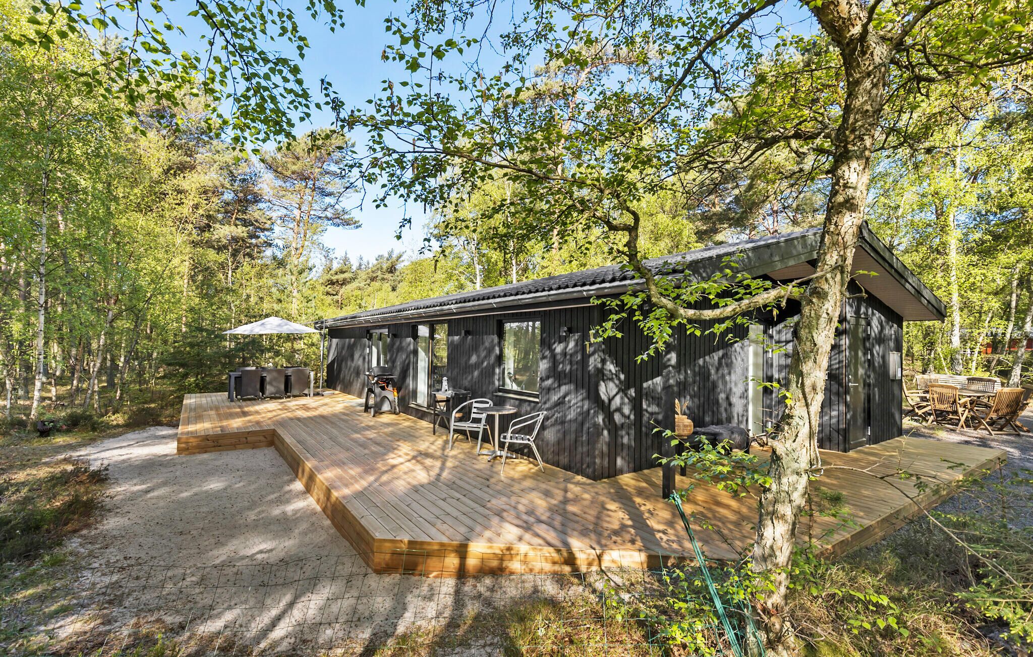 Une cabane en bois dotée d’une terrasse, de meubles de jardin et d’un barbecue.