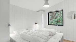 Une chambre à coucher avec un lit, une fenêtre donnant sur des arbres et une lampe fixée au mur.