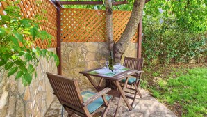 An outdoor seating area with a table and chairs, surrounded by a wooden pergola and a stone wall. - Studio with air conditioning and internet access (Krk)