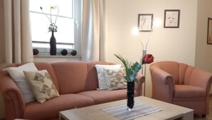 Ein Wohnzimmer mit einer Couch, einem Couchtisch und einer Vase mit Blumen.