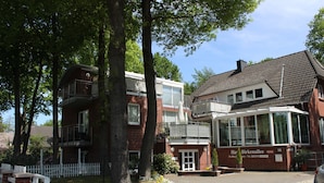 A two-story building with a balcony, a brick facade, and a sign indicating it is a hotel. - Apartment 3 Shell - House Birkenallee / Reckleben GM 69705 (Graal-Müritz)