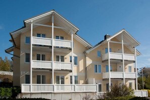 A multi-story residential building with balconies, a flat roof, and a light-colored exterior.