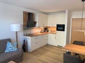 A compact kitchen with white cabinets, a built-in oven, and a coffee maker.