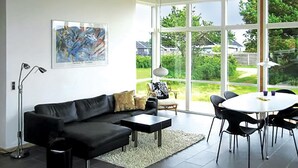 Un salon moderne avec un canapé en cuir noir, une table basse blanche et un coin repas comprenant des chaises noires et une table blanche.