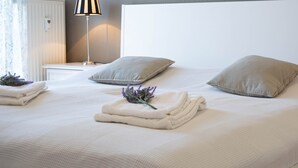 A neatly made bed with pillows, a lamp, and folded towels on a clean, white bedspread. - Dünenstr. 3a Whg.Ki-01. - Ki-Whg. 01 (Kühlungsborn)