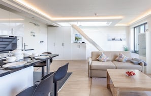Een moderne keuken met een eethoek, een bank en een houten tafel met fruit.