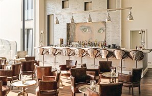 A bar area with a marble countertop, multiple bar stools, and a large mirror. - Lovely apartment in Binz with house sea view (Prora/Rügen)