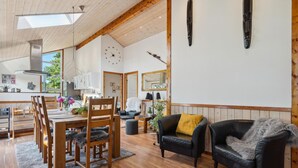 A spacious living area with a wooden dining table, black leather sofas, and a large mirror. - Beautiful home in Tarm with sauna (Tarm)