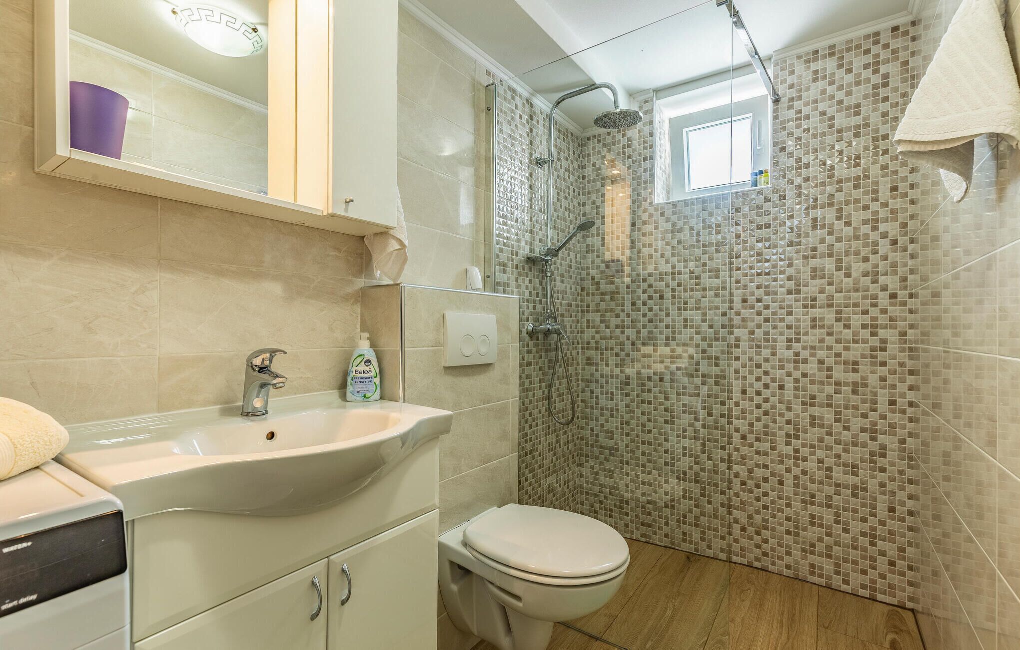 A bathroom with a sink, toilet, and shower.