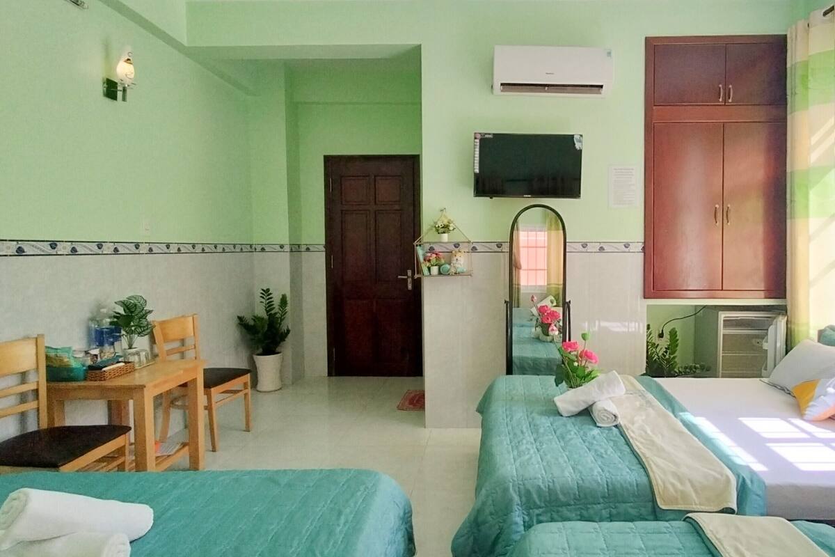 Une chambre d’hôtel avec deux lits, un bureau, une chaise, un miroir et une armoire.