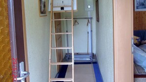 A narrow hallway with a wooden ladder leading to a lofted area.