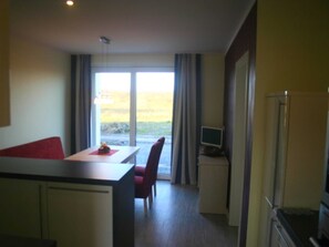 A compact hotel room with a dining area, a small kitchenette, and a view through the window. - Vacation home Hiddensee on the Baltic Sea - Apartment III (Meeresrauschen) (Insel Hiddensee)