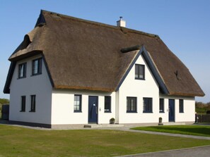 A traditional thatched-roof house with a symmetrical facade, multiple windows, and a central door. - Vacation home Hiddensee on the Baltic Sea - Apartment III (Meeresrauschen) (Insel Hiddensee)