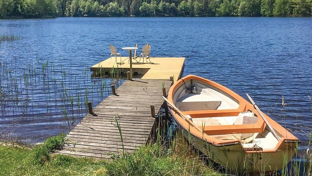 Une jetée en bois s’avançant dans un lac, avec un petit bateau amarré à celle-ci.