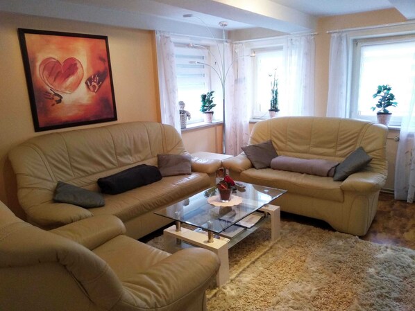A living room with two beige sofas, a glass coffee table, and a large abstract painting on the wall.