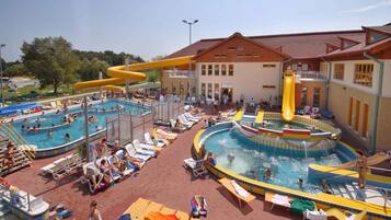 A pool area with multiple swimming pools, sun loungers, and a water slide.