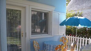 A patio with a table and chairs, a white picket fence, and a blue umbrella. - Holiday apartment only 150 m from the spa (Zalakaros)