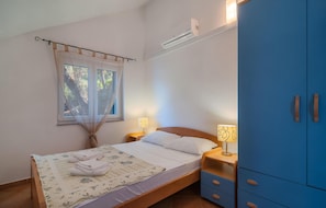 Een slaapkamer met een bed, nachtkastjes, een kledingkast en een airconditioning.