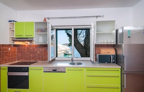 Een moderne keuken met groene kastjes, een Bosch vaatwasser, een Samsung magnetron en een roestvrijstalen koelkast.