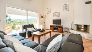 Ein Wohnzimmer mit einer Couch, einem Couchtisch, einem Fernseher und einem Kamin.