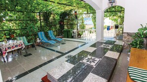 Un jardín interior soleado con asientos, suelo a cuadros y vistas al exterior.