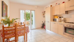 A kitchen with wooden cabinets, a microwave, a stove, and a dining area with a table and chairs. - Lovely home in Dolcedo -IM- with WiFi (Dolcedo -IM-)