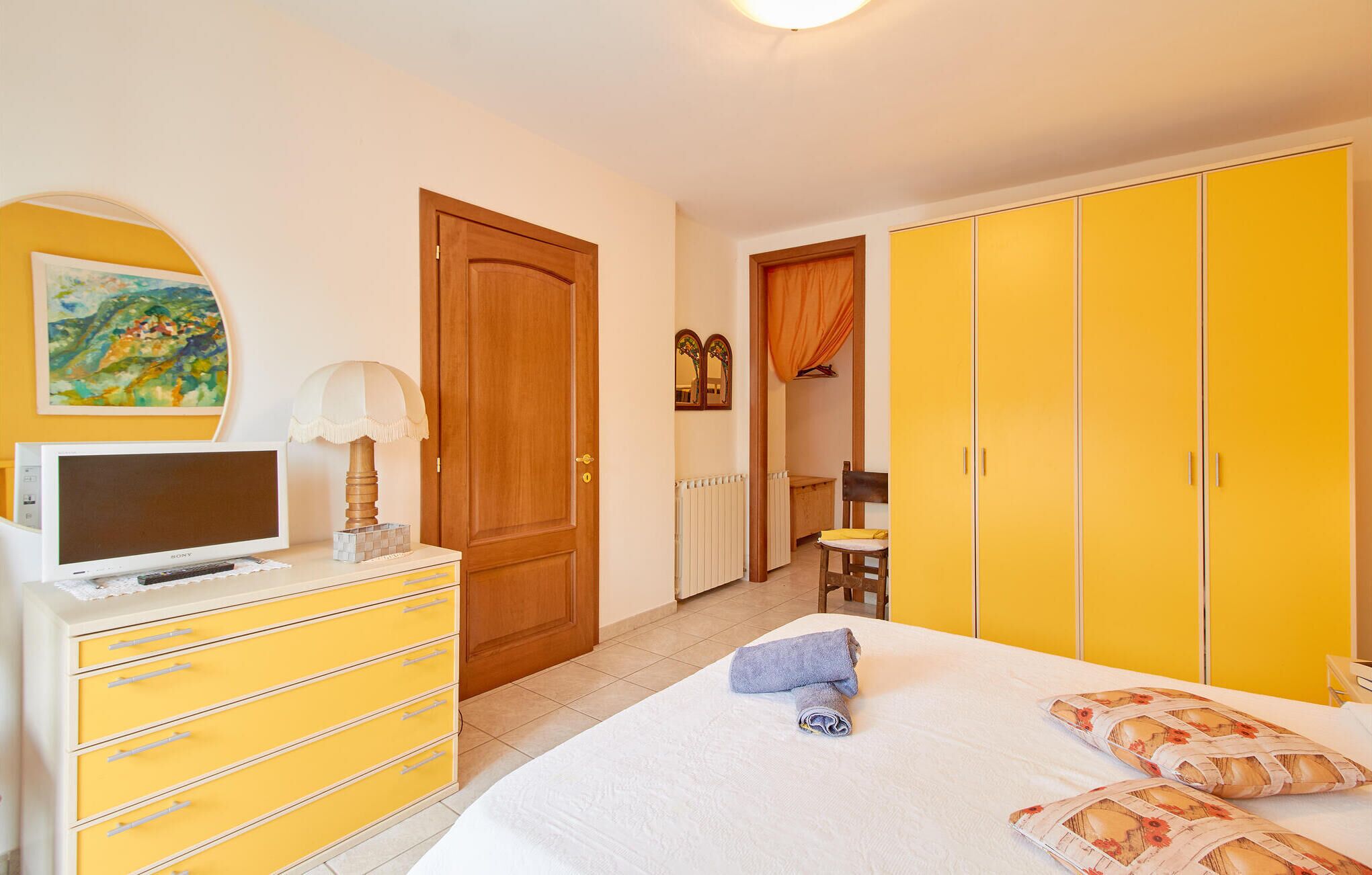 A bedroom with a bed, a dresser, a television, and a wardrobe.
