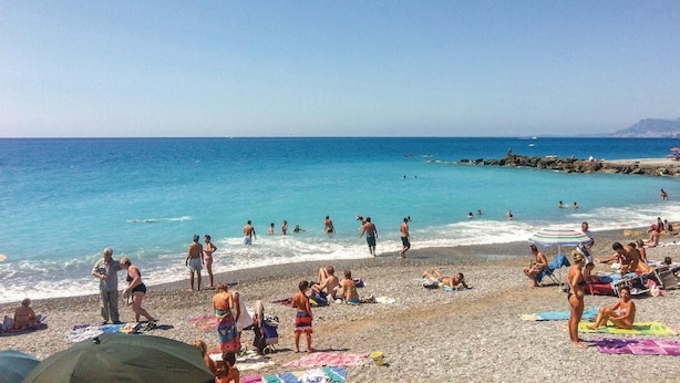 A beach with people sunbathing and swimming, a rocky shoreline, and a clear blue sea. - Lovely home in Dolcedo -IM- with WiFi (Dolcedo -IM-)