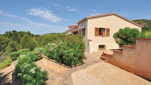 A two-story house with a stone pathway leading to the entrance, surrounded by lush greenery and flowering plants. - Domaine de la Bastide d'Agay (Agay)
