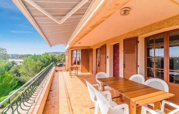 A balcony with a wooden table and chairs, a grill, and a view of the surrounding greenery. - Domaine de la Bastide d'Agay (Agay)