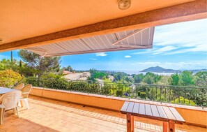A balcony with a table and chairs, a pergola, and a scenic view of a coastal landscape. - Domaine de la Bastide d'Agay (Agay)