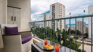 Un balcon avec un fauteuil en osier, une assiette de croissants et deux verres de jus d’orange.
