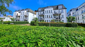 Un immeuble d’appartements moderne, doté de nombreux balcons et d’un jardin bien entretenu en premier plan.
