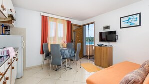 Une chambre d’hôtel compacte comprenant un coin repas, une télévision et une vue sur la mer.