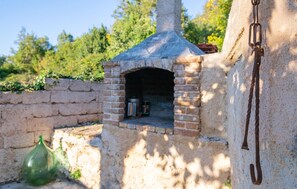 Outdoor brick oven with chimney and metal chain, perfect for cooking and baking in a casual setting.