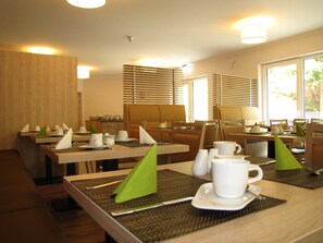 Ruokailutila, jossa on useita pöytiä, tuoleja ja buffetpöytä.