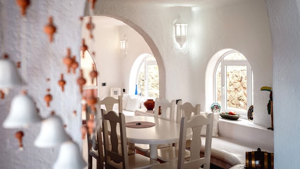 A dining area with white furniture, arched windows, and decorative wall elements.