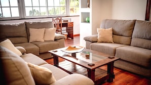 A living room with two beige sofas, a wooden coffee table, and a wooden floor.