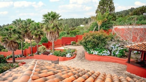 A courtyard with red walls, palm trees, and a tiled roof.