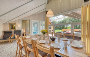 Un espace repas avec une longue table en bois dressée pour le repas, entourée de chaises en bois.