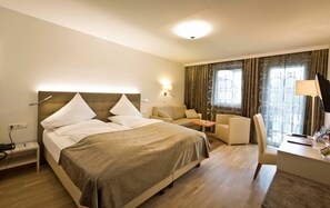 Een hotelkamer met een bed, een bank, een bureau met lamp en een televisie.
