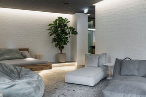 Une chambre moderne avec un lit, un canapé, une petite table et une plante en pot.