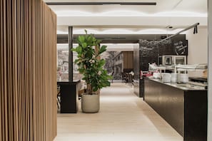 A modern kitchen with a central island, a potted plant, and a chalkboard menu.