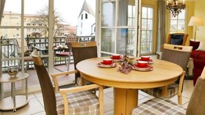 A dining area with a round table, chairs, and a view of a building in the background. - (1) 3 room apartment - sea views - apartment block "Atlantic" (Kühlungsborn)